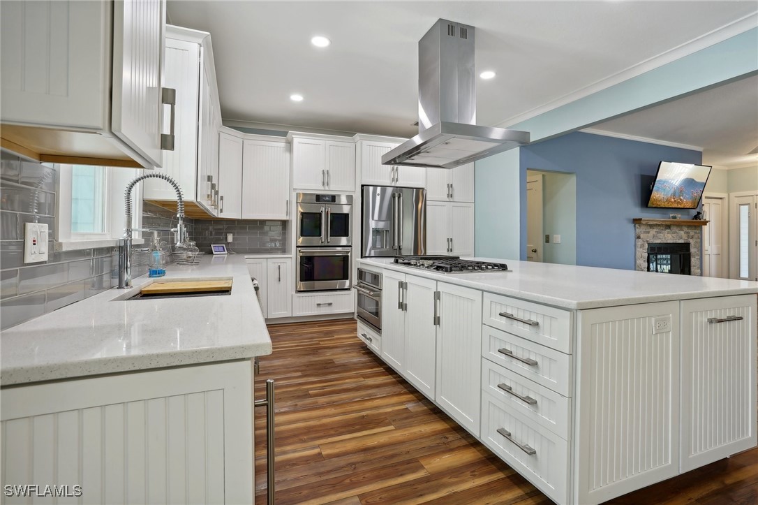 8335 Main Street Bokeelia, FL 33922 - Photo 23 of 47 a kitchen with kitchen island granite countertop a sink and white cabinets with wooden floor