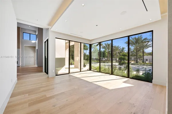a view of an empty room with kitchen and window