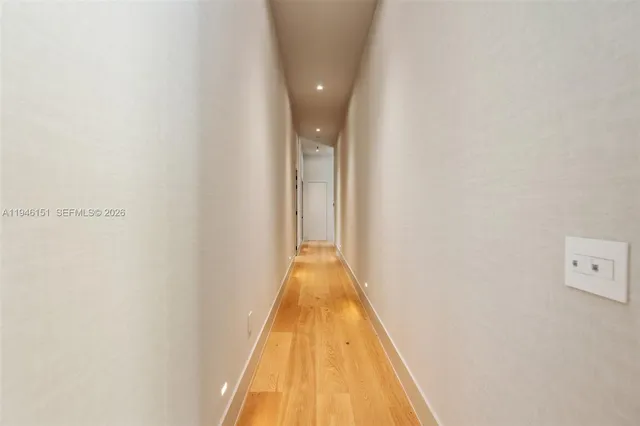 a view of a hallway with wooden floor and a bathroom