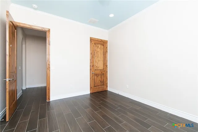 a view of an empty room with wooden floor and closet