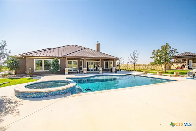 a view of swimming pool with lawn chairs and plants