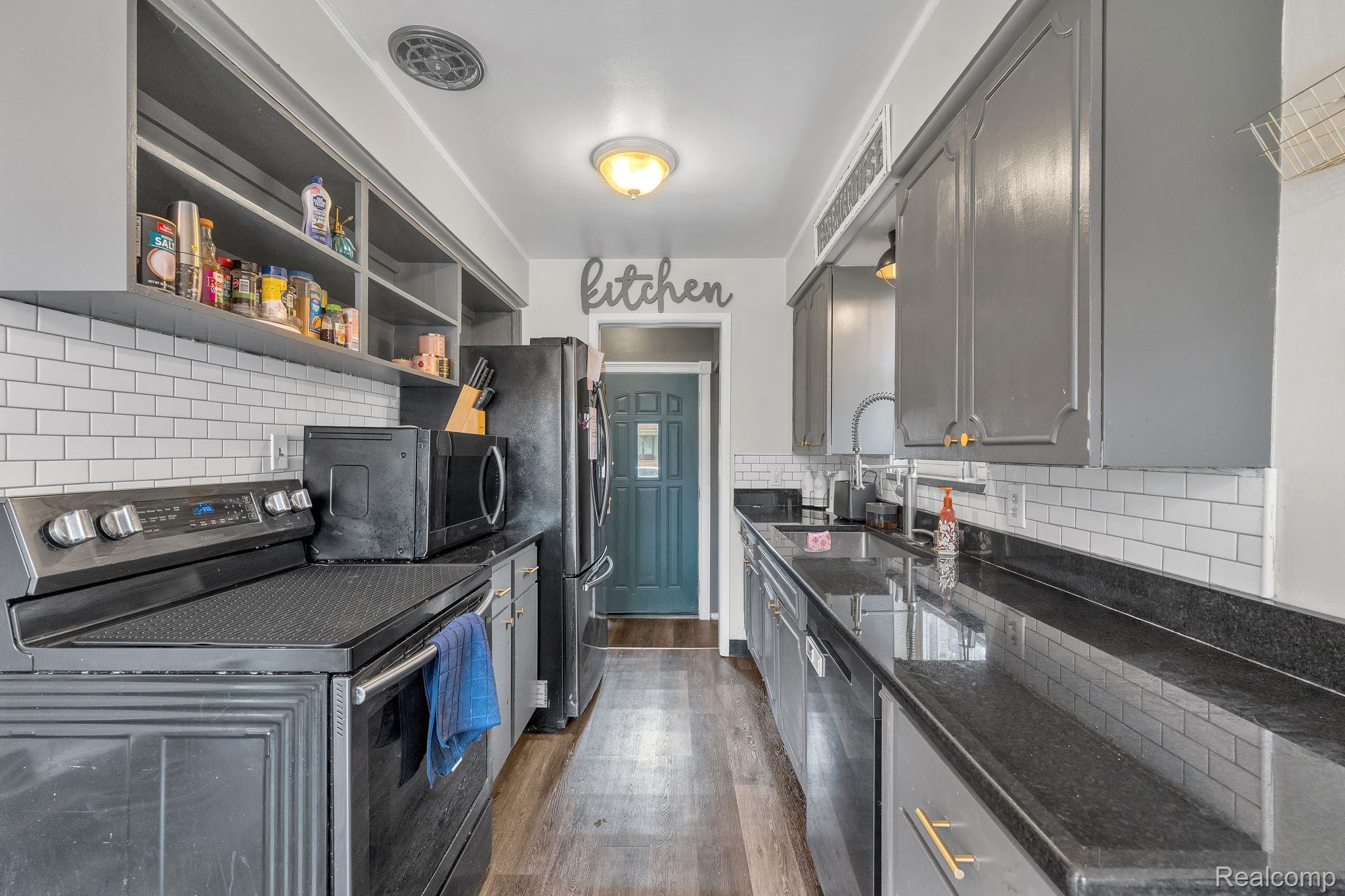 37022 Pinewood Road Wayne, MI 48184 - Photo 17 of 30 Kitchen featuring stainless steel appliances, gray cabinets, dark wood-style flooring, decorative backsplash, and dark stone countertops