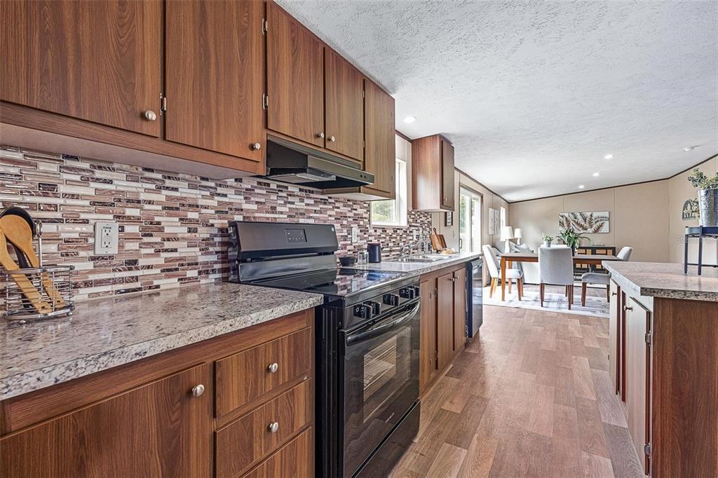 8150 Cherokee Road Bartow, FL 33830 - Photo 15 of 35 a kitchen with stainless steel appliances granite countertop a stove top oven a sink dishwasher and cabinets with wooden floor