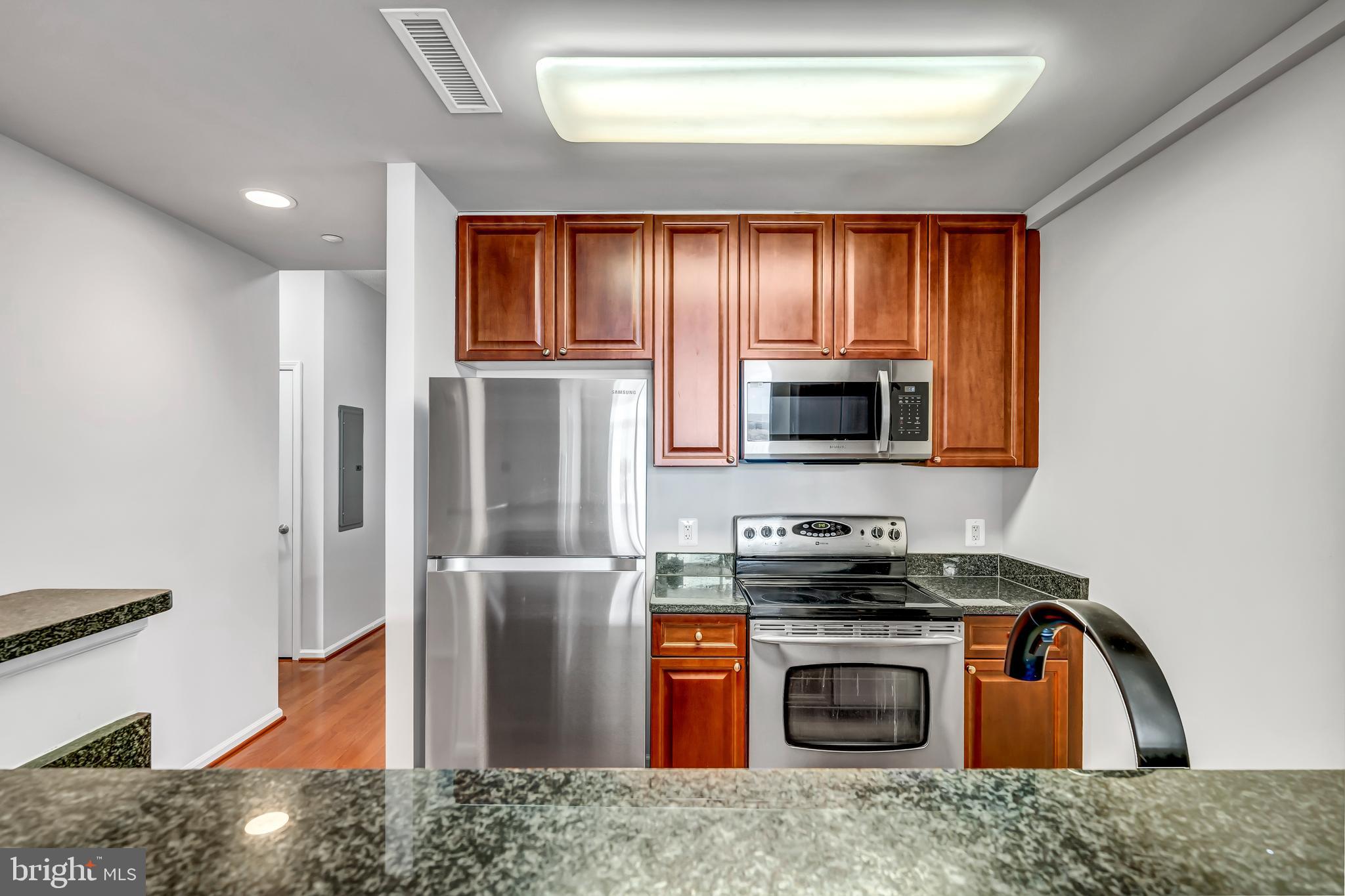 11700 Old Georgetown Road, Unit 1314 North Bethesda, MD 20852 - Photo 16 of 29 a kitchen with stainless steel appliances granite countertop a refrigerator a stove and a sink with wooden floor