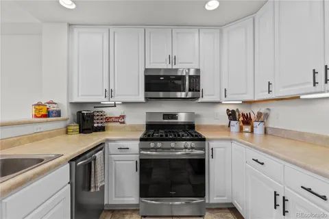 a kitchen with granite countertop white cabinets and stainless steel appliances