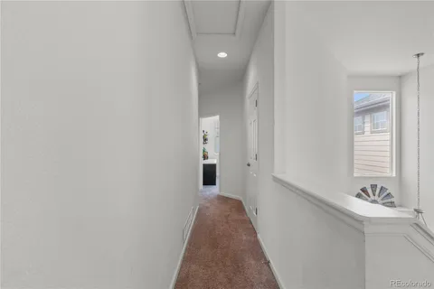 a view of a hallway with wooden floor and a bathroom