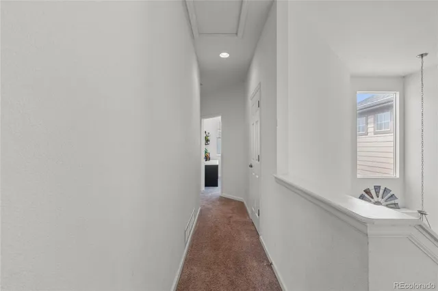 a view of a hallway with wooden floor and a bathroom