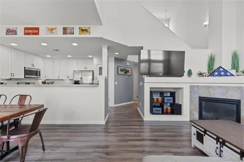 a living room with stainless steel appliances furniture a fireplace a flat screen tv and a window