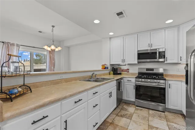 a kitchen with stainless steel appliances granite countertop a stove a sink and a microwave