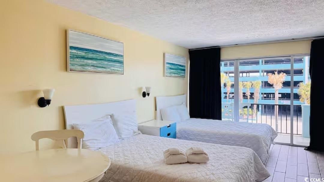 1600 South Ocean Boulevard, Unit 322 Myrtle Beach, SC 29577 - Photo 12 of 16 Bedroom featuring access to exterior, a textured ceiling, and wood finished floors