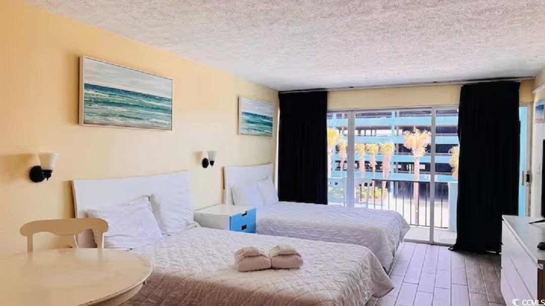 1600 South Ocean Boulevard, Unit 322 Myrtle Beach, SC 29577 - Photo 14 of 16 Bedroom featuring access to exterior, wood finished floors, and a textured ceiling