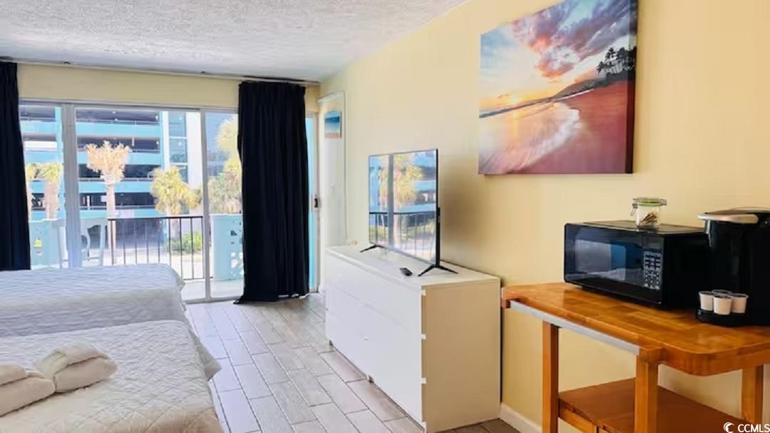 1600 South Ocean Boulevard, Unit 322 Myrtle Beach, SC 29577 - Photo 7 of 16 Bedroom with access to exterior, wood finish floors, and a textured ceiling