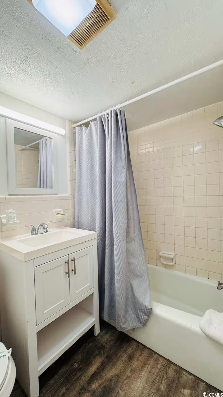 1600 South Ocean Boulevard, Unit 322 Myrtle Beach, SC 29577 - Photo 10 of 16 Bathroom with a textured ceiling, shower / bath combo, vanity, and dark wood finished floors