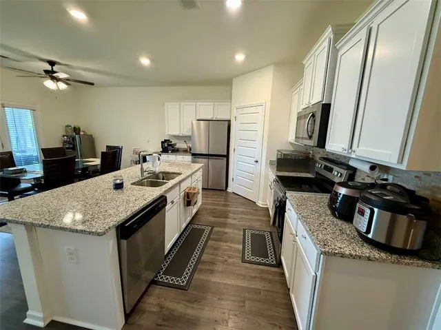 a large kitchen with stainless steel appliances granite countertop a sink stove and refrigerator