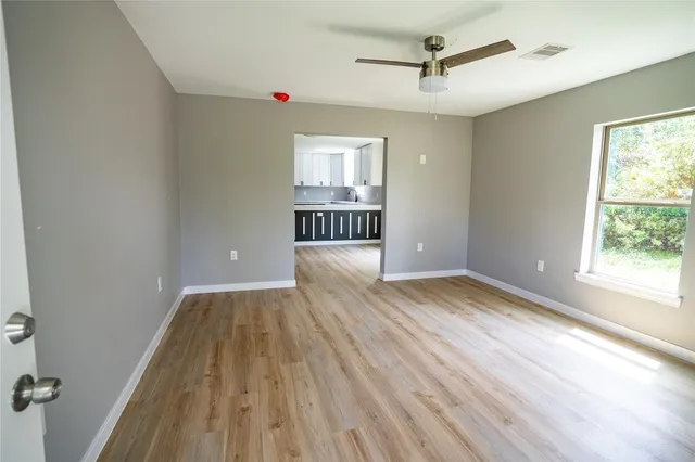an empty room with wooden floor and windows