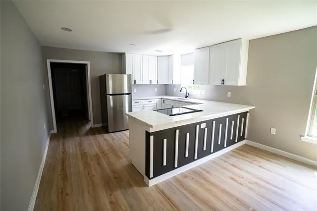 a kitchen that has a lot of cabinets a sink and wooden floor