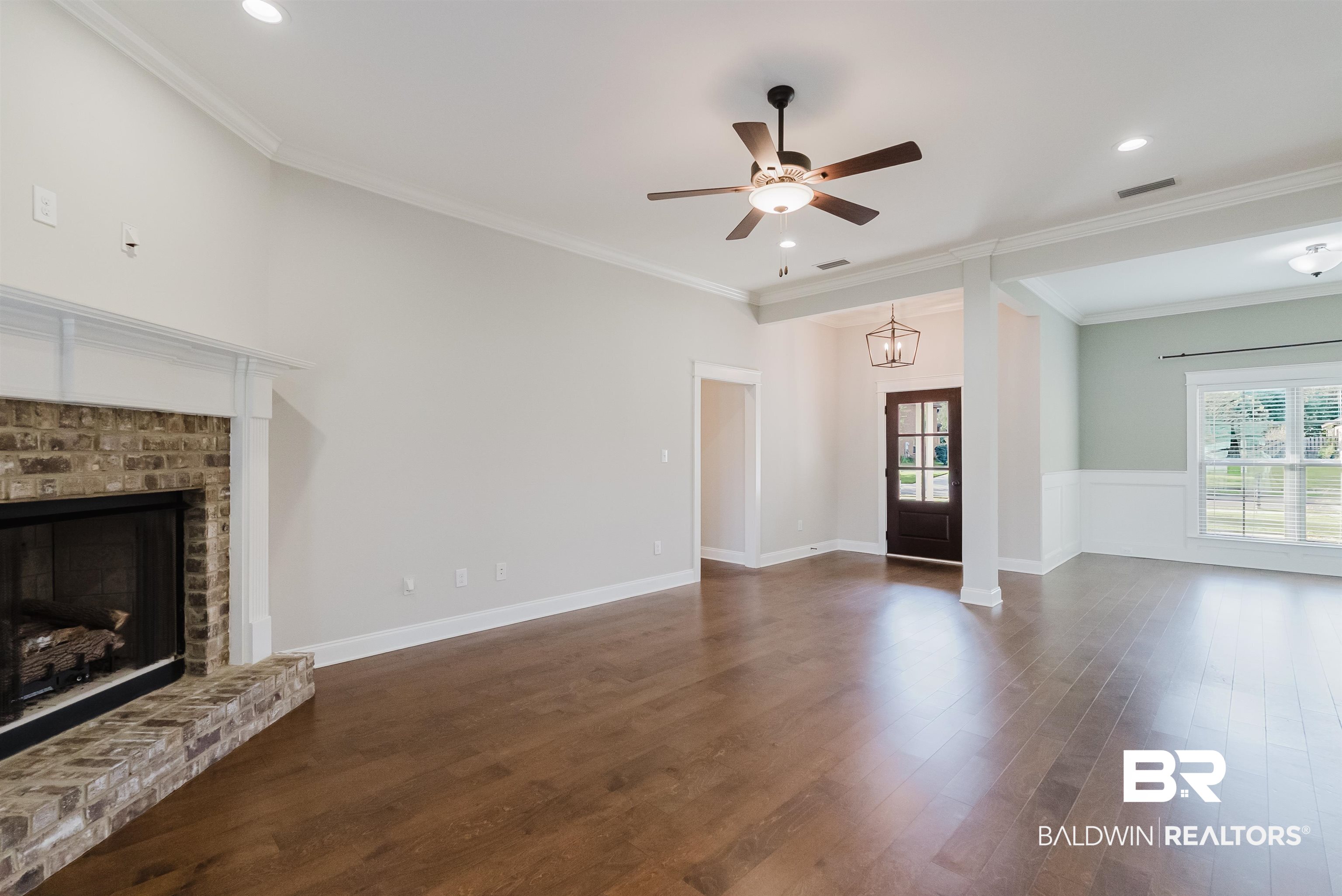 237 Hawthorne Circle Fairhope, AL 36532 - Photo 4 of 14 Unfurnished living room with dark wood-style floors, ornamental molding, a ceiling fan, a brick fireplace, and recessed lighting