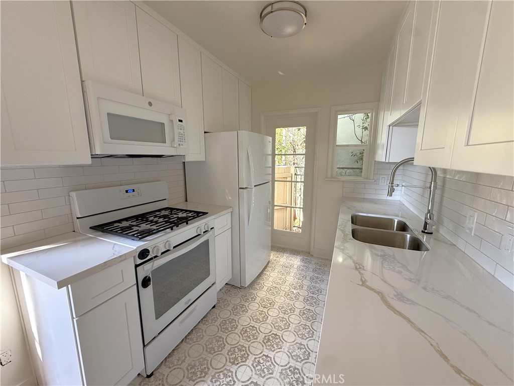 1007 9th Street, Unit 1 Santa Monica, CA 90403 - Photo 7 of 17 a kitchen with granite countertop a sink a stove and refrigerator