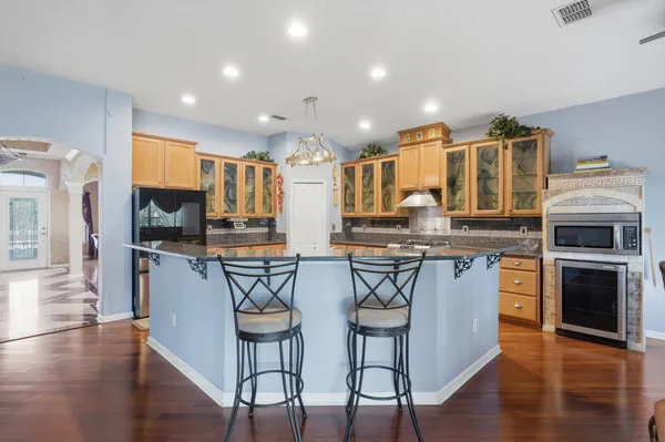 a kitchen with stainless steel appliances granite countertop a stove top oven a refrigerator a sink and a dining table with wooden floor