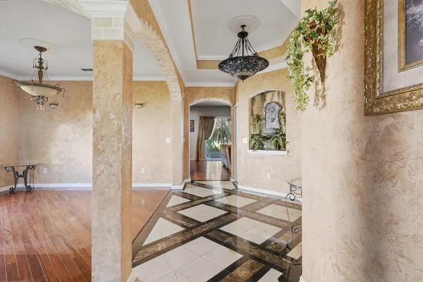 a view of a hallway with a dining area a chandelier and wooden floor