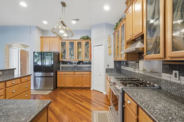 a kitchen with stainless steel appliances granite countertop wooden cabinets and a stove top oven