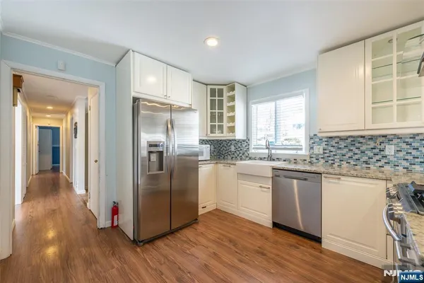 a kitchen with stainless steel appliances granite countertop a refrigerator a sink dishwasher a stove with wooden floors and cabinets