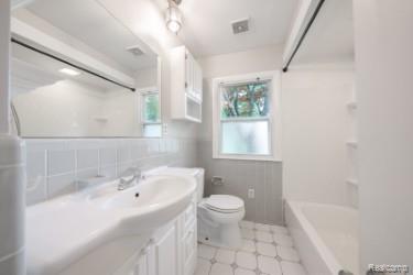 2329 Rutherford Road Bloomfield Hills, MI 48302 - Photo 43 of 46 Full bathroom featuring a white vanity with integrated sink, coordinating wall-mounted storage cabinet, white subway tile wainscoting, and patterned floor tiling