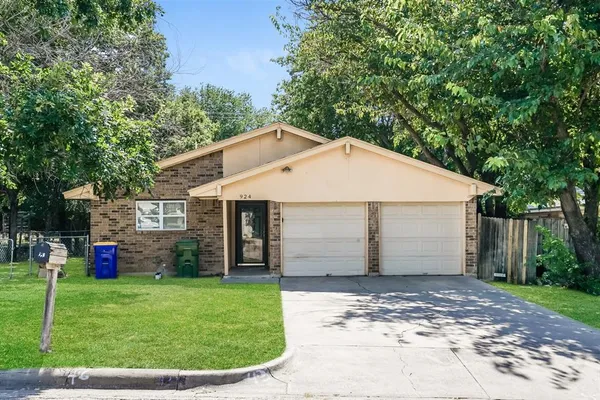 a view of a white house with a small yard and large trees