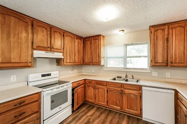 a kitchen with granite countertop wooden cabinets a sink and white appliances