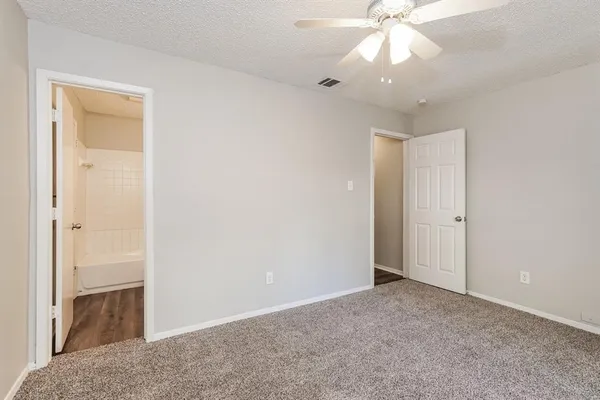 a view of an empty room and chandelier fan