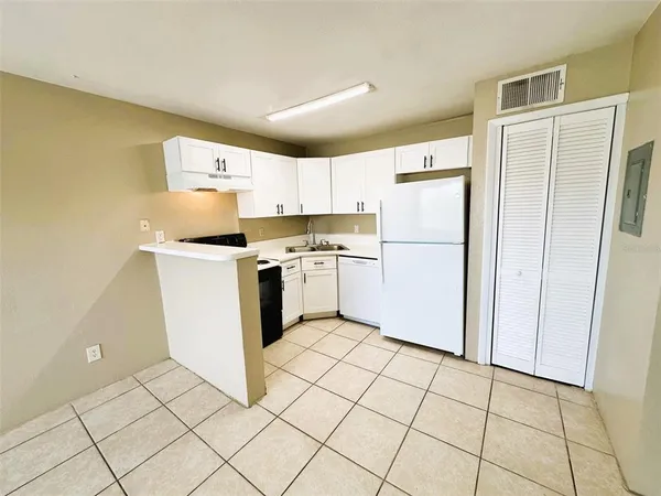 a kitchen with white cabinets a refrigerator and a stove