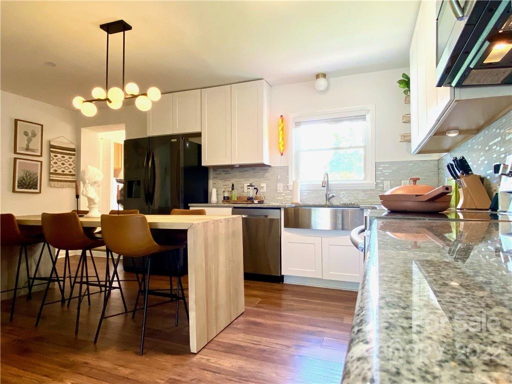 1240 Skyview Road Charlotte, NC 28208 - Photo 10 of 30 a kitchen with stainless steel appliances granite countertop a stove top oven a refrigerator a dining table and chairs with wooden floor