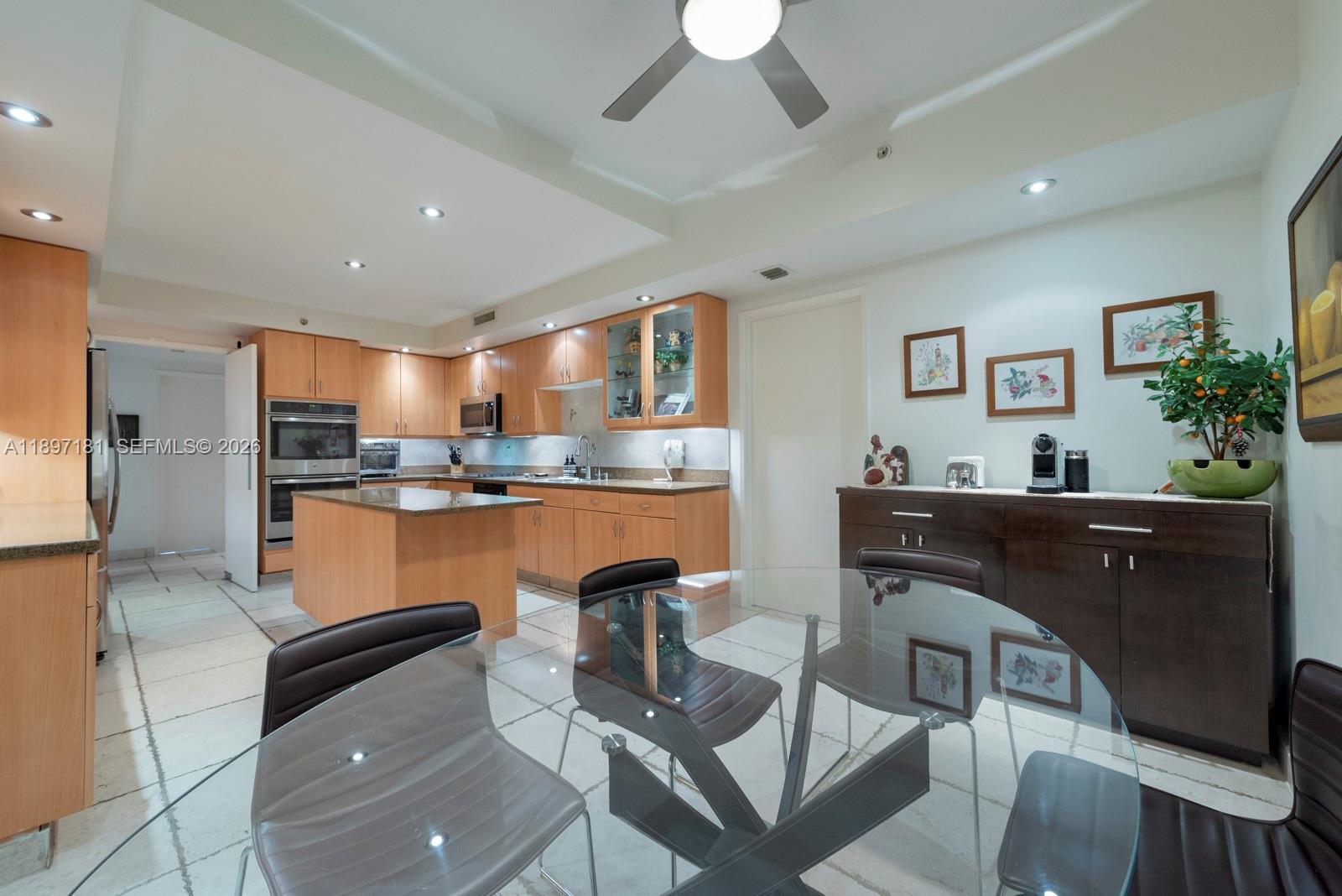 765 Crandon Boulevard, Unit 102 Key Biscayne, FL 33149 - Photo 23 of 37 a kitchen with stainless steel appliances granite countertop a refrigerator a stove a sink dishwasher with a dining table and chairs