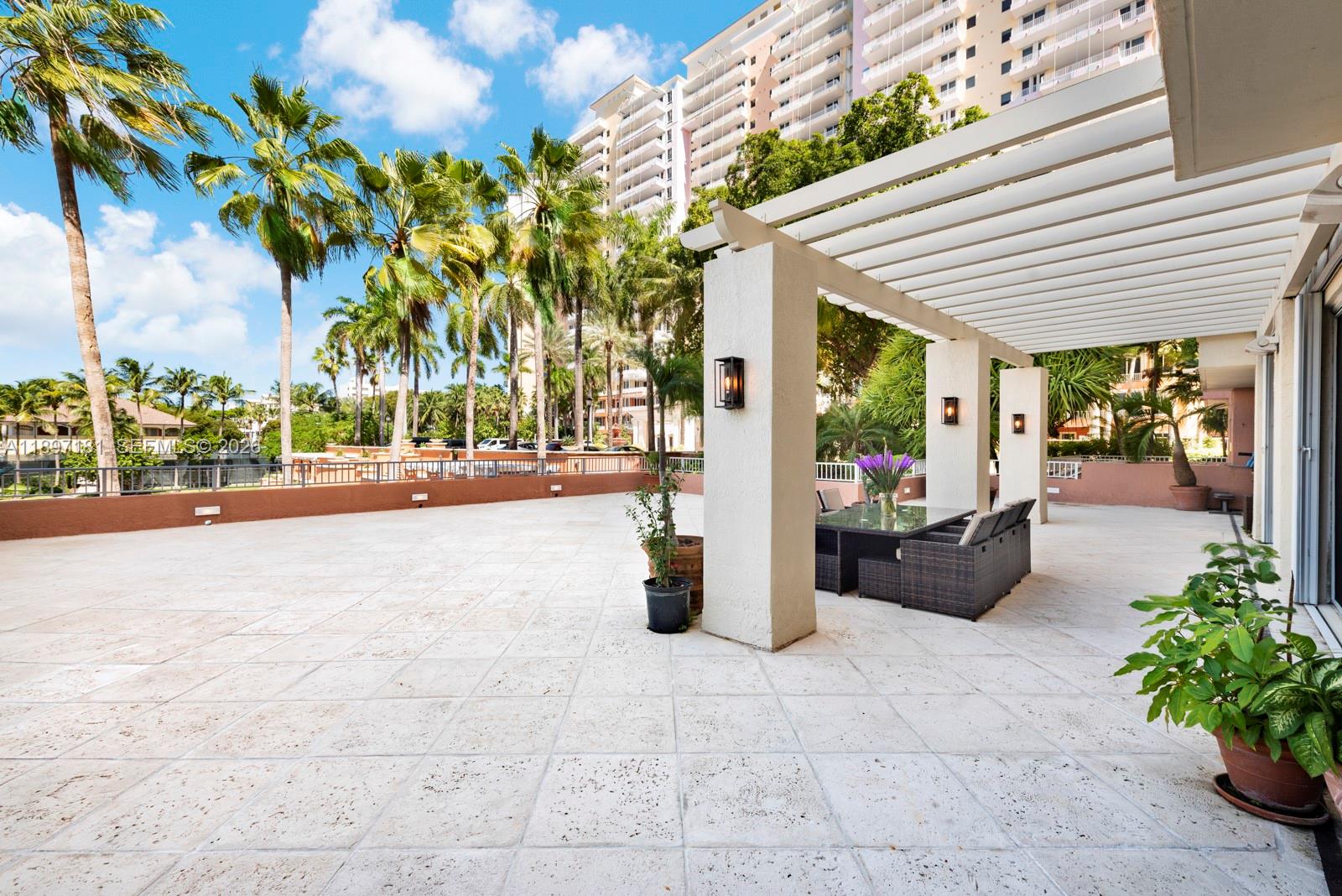 765 Crandon Boulevard, Unit 102 Key Biscayne, FL 33149 - Photo 7 of 37 a view of a patio with table and chairs potted plants and palm trees