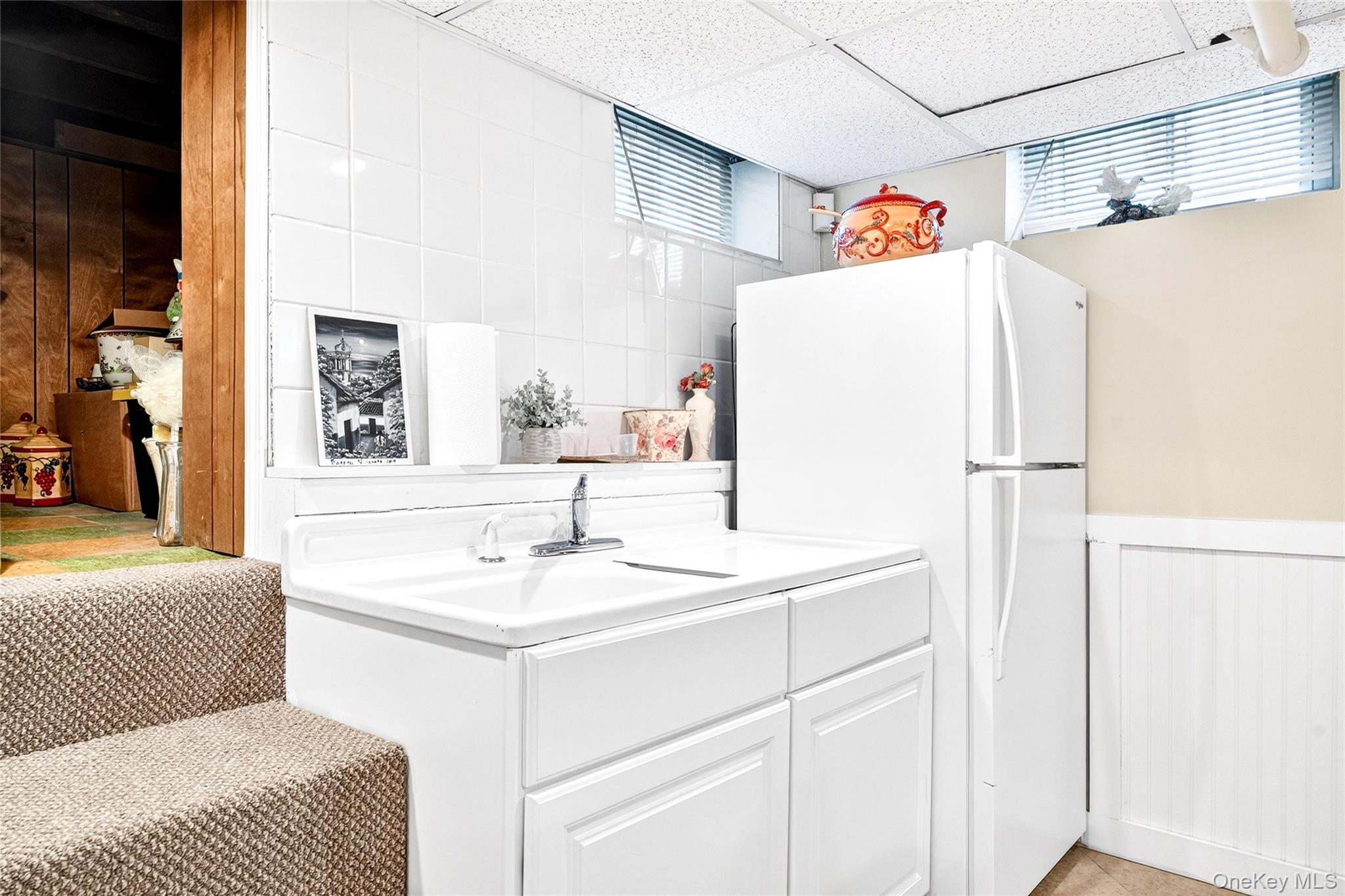 3334 Country Club Road Bronx, NY 10465 - Photo 44 of 49 Kitchen with freestanding refrigerator, a wainscoted wall, a drop ceiling, white cabinets, and light countertops