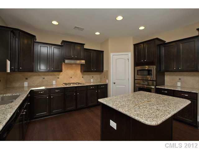 86587 Arrington Road, Unit 101 Lancaster, SC 29720 - Photo 8 of 16 a kitchen with kitchen island granite countertop wooden cabinets a refrigerator and granite counter tops
