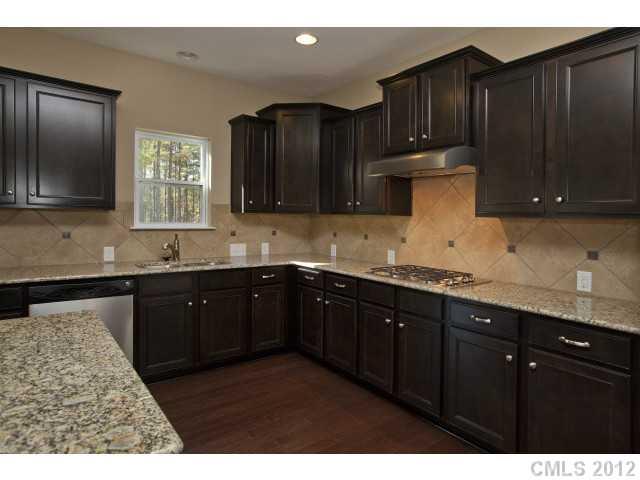 86587 Arrington Road, Unit 101 Lancaster, SC 29720 - Photo 9 of 16 a kitchen with granite countertop wooden cabinets a sink and dishwasher