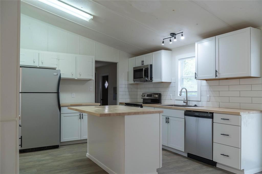 4817 Creekside Road Melissa, TX 75454 - Photo 4 of 10 a kitchen with kitchen island a sink stainless steel appliances and cabinets