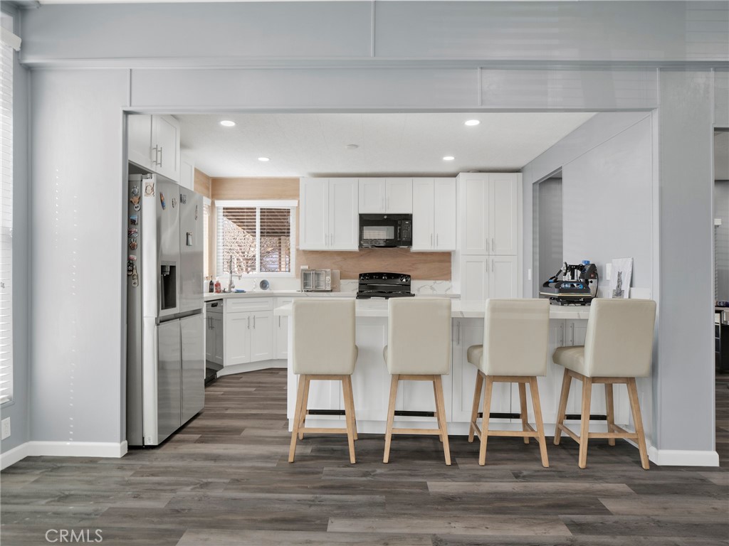 24303 Woolsey Canyon Road, Unit 85 West Hills, CA 91304 - Photo 5 of 31 a kitchen with microwave a refrigerator and chairs