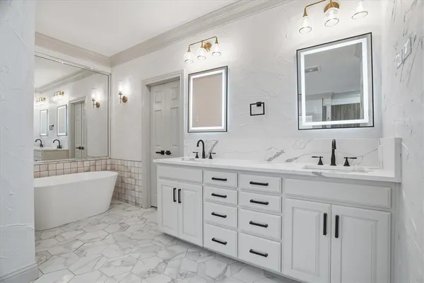 a spacious bathroom with double sink a mirror a bathtub and a window