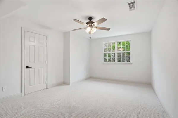 an empty room with windows and fan