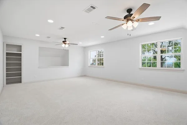 an empty room with windows and ceiling fan