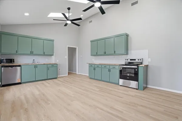 a kitchen with stainless steel appliances granite countertop a sink cabinets and wooden floor