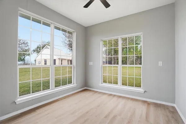 a view of an empty room with a window and wooden floor