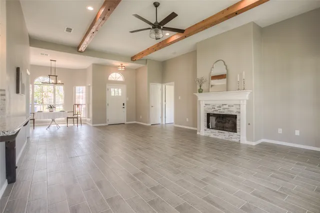 a view of a livingroom with a fireplace a ceiling fan and wooden floor