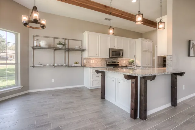 a kitchen with kitchen island granite countertop a sink cabinets and stainless steel appliances