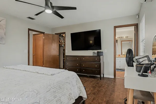 a bedroom with a bed and a flat tv screen on dresser
