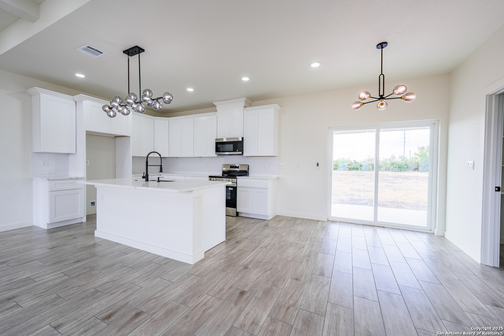 122 Ranchero Way Natalia, TX 78059 - Photo 11 of 31 a view of a kitchen with a center island wooden floor and a large window