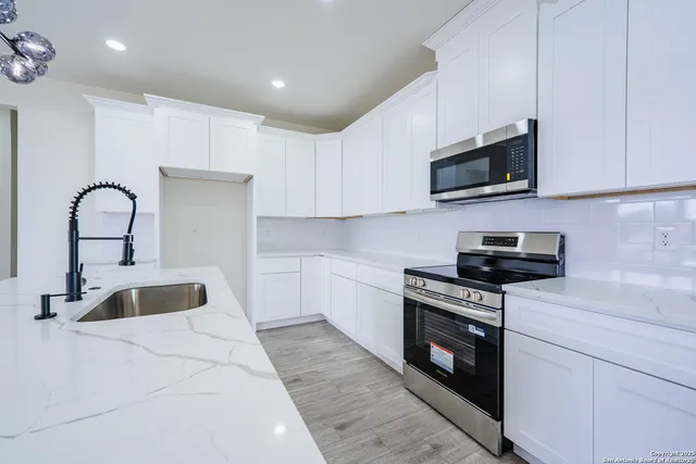 a kitchen with stainless steel appliances granite countertop a sink a stove and a microwave