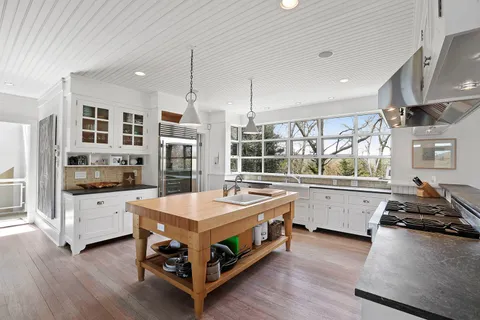 a kitchen with stainless steel appliances a stove a sink and white cabinets with wooden floor